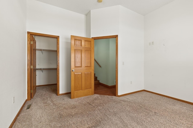 unfurnished bedroom with a walk in closet, light carpet, and a closet