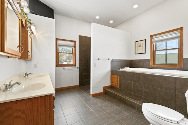 bathroom featuring a relaxing tiled tub, plenty of natural light, tile patterned floors, and toilet