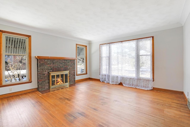 unfurnished living room with a brick fireplace, crown molding, and light hardwood / wood-style floors