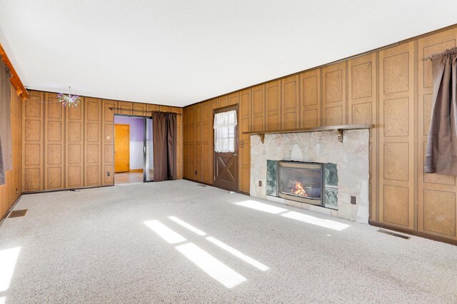 unfurnished living room featuring light colored carpet and wooden walls