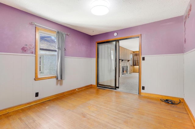 unfurnished room with light hardwood / wood-style floors and a textured ceiling