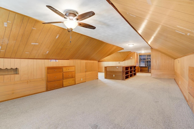 additional living space featuring ceiling fan, vaulted ceiling, light carpet, and wood walls