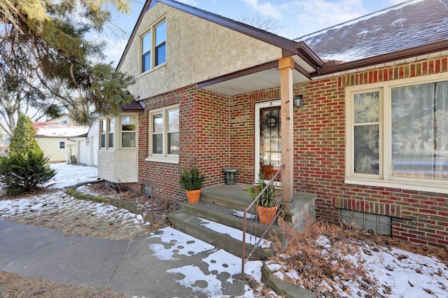 view of front facade featuring brick siding, stucco siding, and roof with shingles