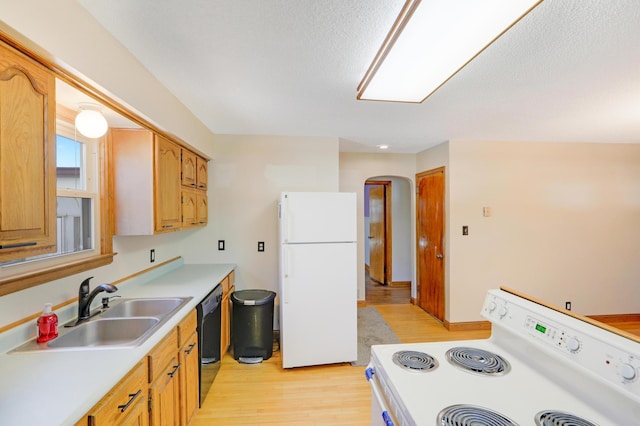 kitchen with white appliances, arched walkways, a sink, light countertops, and light wood-style floors