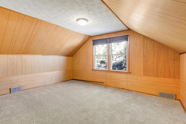 additional living space with vaulted ceiling, visible vents, wood walls, and carpet floors