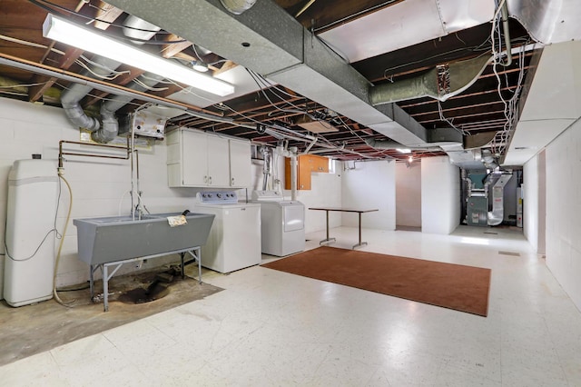 unfinished below grade area featuring heating unit, washing machine and dryer, light floors, and a sink