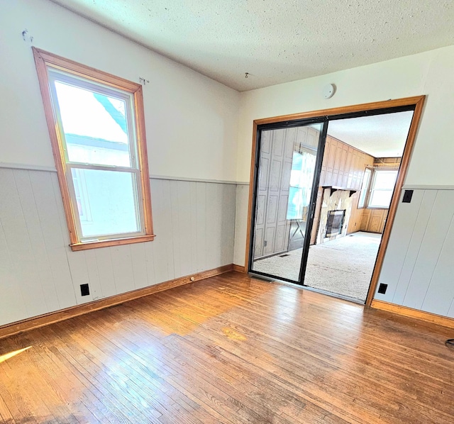 unfurnished room with hardwood / wood-style floors, a textured ceiling, and wainscoting