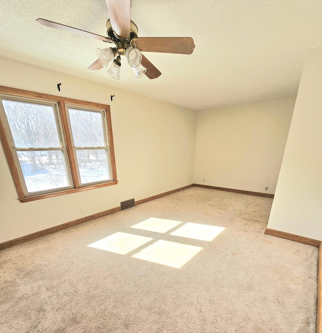 empty room with visible vents, a ceiling fan, a textured ceiling, carpet, and baseboards