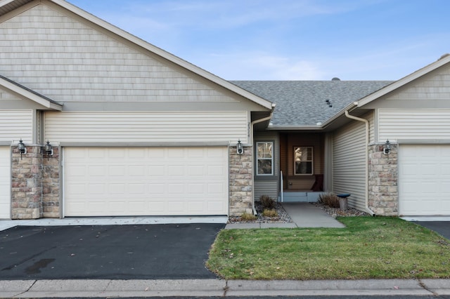 view of front of house featuring a garage, stone siding, a shingled roof, and aphalt driveway