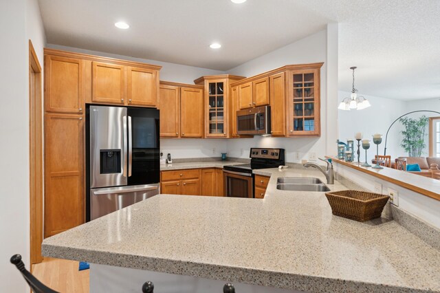 kitchen with recessed lighting, stainless steel appliances, a peninsula, a sink, and glass insert cabinets