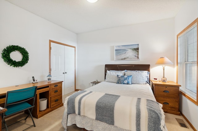 bedroom with light carpet, baseboards, visible vents, and a closet