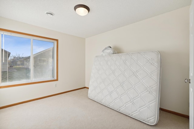 unfurnished bedroom featuring baseboards, a textured ceiling, and light colored carpet