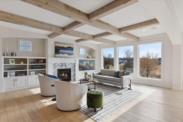 living room with beam ceiling, a tile fireplace, and light hardwood / wood-style flooring