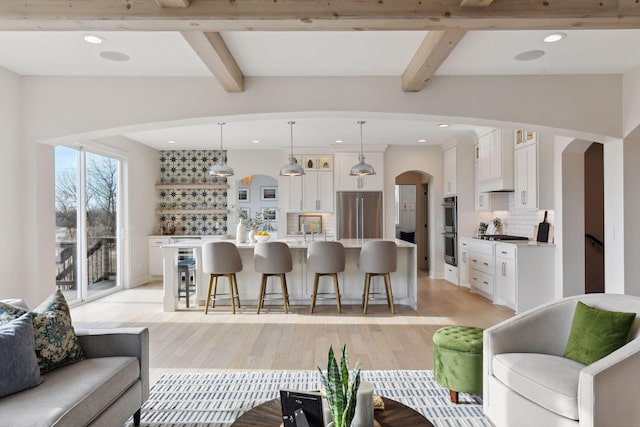 kitchen with pendant lighting, white cabinetry, appliances with stainless steel finishes, and an island with sink