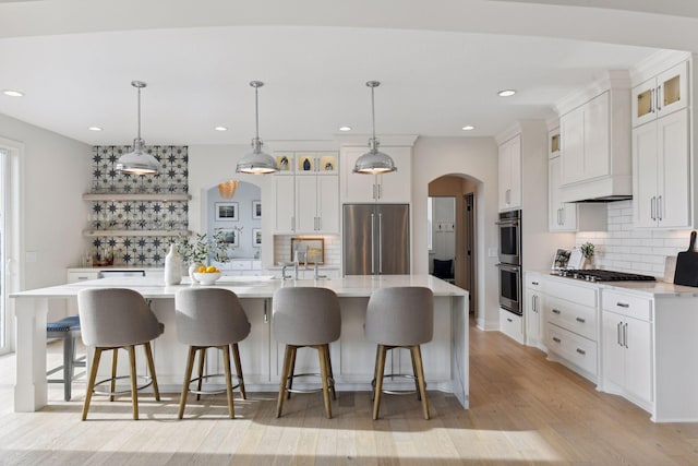 kitchen with white cabinetry, appliances with stainless steel finishes, a large island, and decorative light fixtures