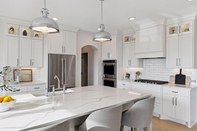 kitchen featuring appliances with stainless steel finishes, white cabinets, and decorative light fixtures