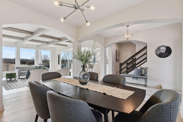 dining area with beamed ceiling, coffered ceiling, an inviting chandelier, and light hardwood / wood-style floors