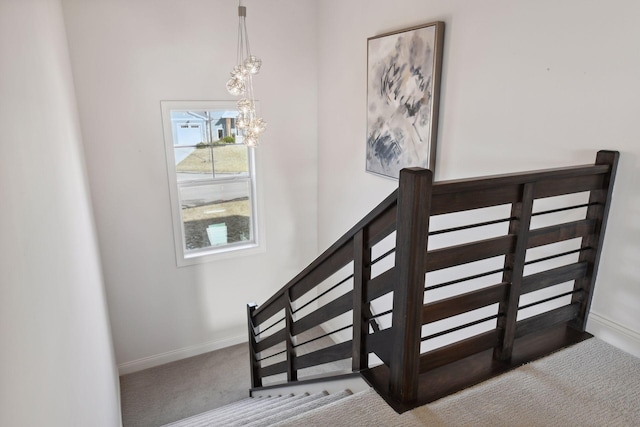 stairway featuring an inviting chandelier and carpet flooring