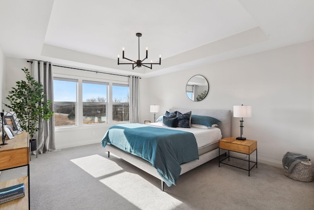 bedroom with a notable chandelier, a tray ceiling, and carpet flooring