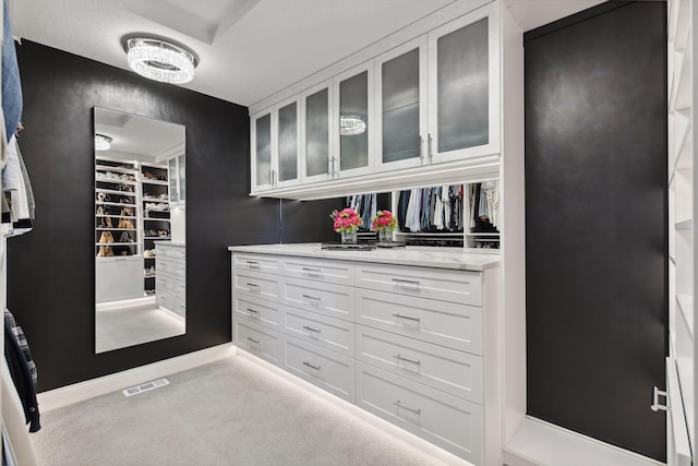 walk in closet with light colored carpet