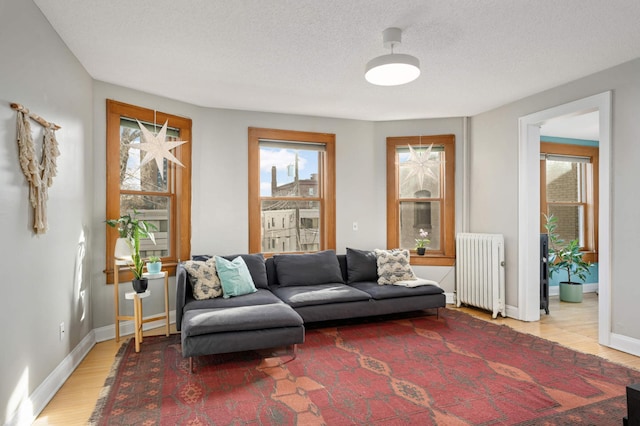 living room featuring radiator, light hardwood / wood-style flooring, and a textured ceiling