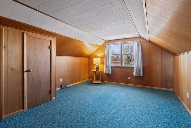 additional living space with vaulted ceiling, wooden walls, and carpet floors