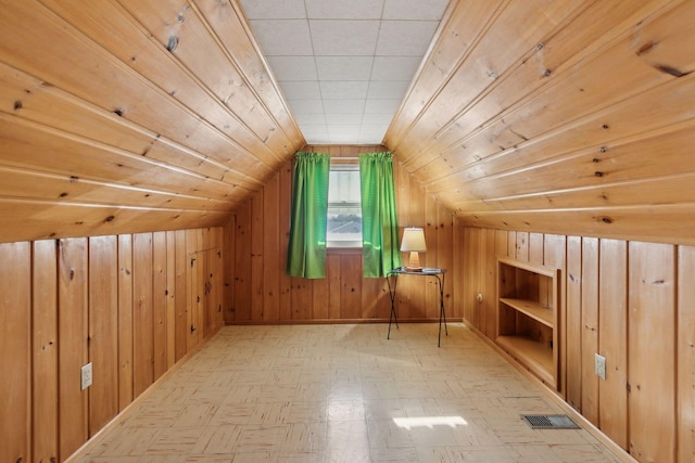 additional living space with lofted ceiling, wood ceiling, and wooden walls