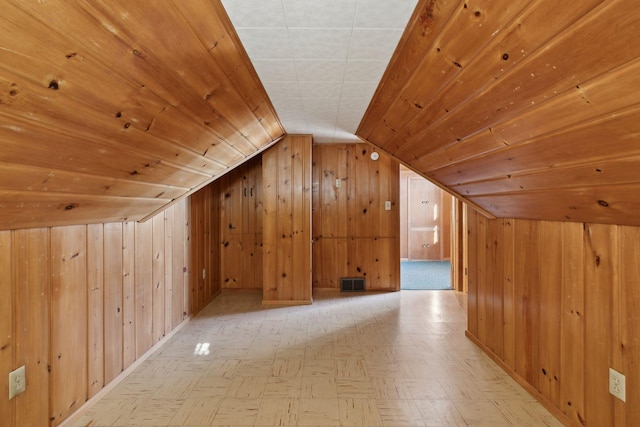 additional living space with lofted ceiling, wooden ceiling, and wooden walls