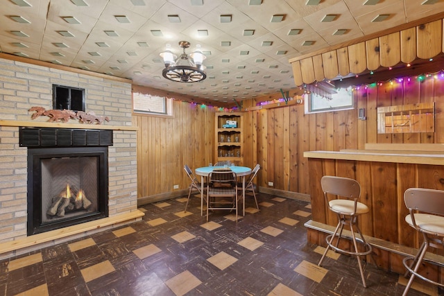 dining space featuring bar, a fireplace, and wood walls