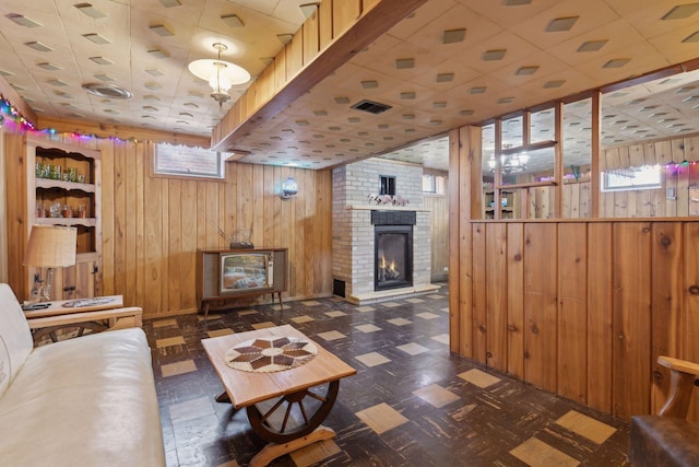 living room featuring plenty of natural light, a fireplace, and wood walls