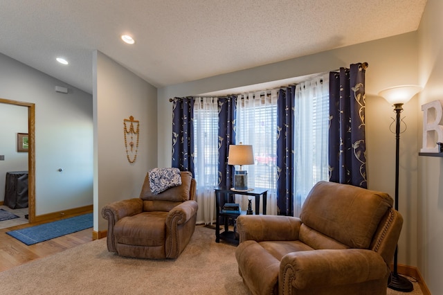 sitting room with light hardwood / wood-style floors, vaulted ceiling, and a textured ceiling