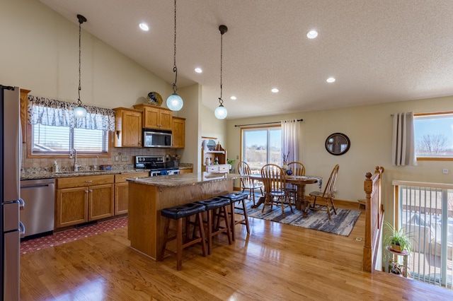 kitchen with stone countertops, sink, a kitchen bar, a center island, and stainless steel appliances