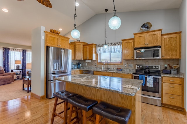 kitchen with a kitchen island, decorative light fixtures, sink, a kitchen breakfast bar, and stainless steel appliances