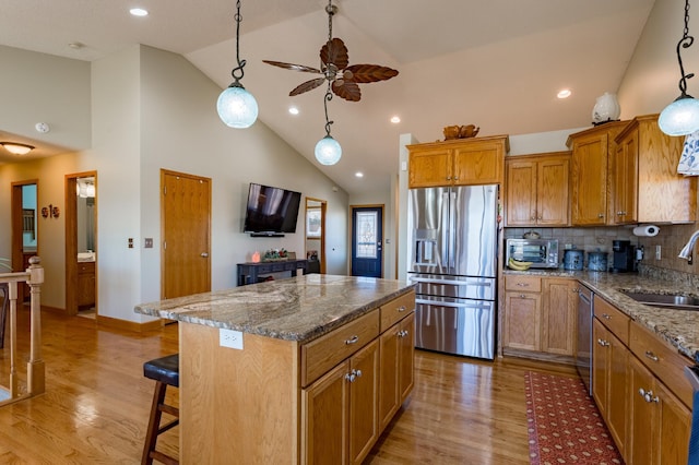 kitchen featuring pendant lighting, a breakfast bar, a kitchen island, stainless steel appliances, and stone countertops