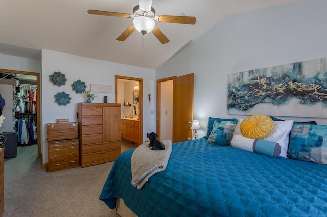 carpeted bedroom featuring vaulted ceiling, a walk in closet, ceiling fan, ensuite bath, and a closet