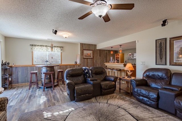 living room featuring hardwood / wood-style floors, a textured ceiling, and wood walls