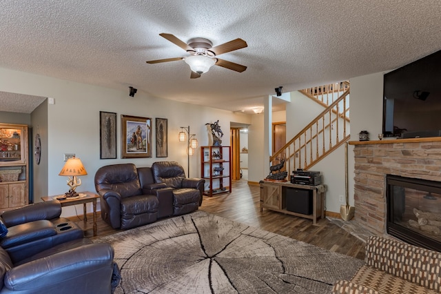 living room with ceiling fan, wood-type flooring, a fireplace, and a textured ceiling