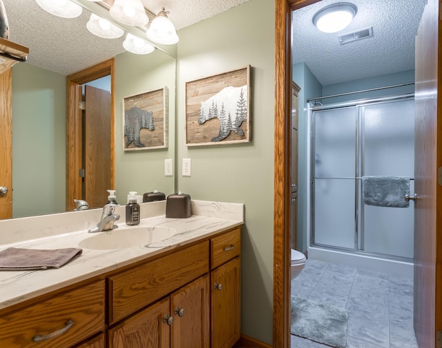 bathroom with an enclosed shower, toilet, and a textured ceiling