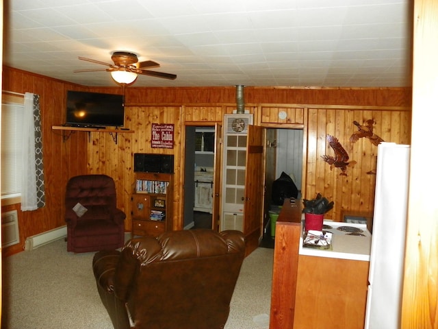 living room with a baseboard radiator, wood walls, ceiling fan, and carpet