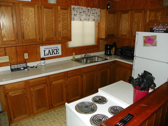 kitchen with white refrigerator, sink, and wooden walls