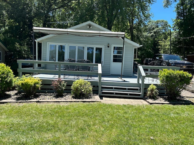 back of property featuring a deck and a lawn