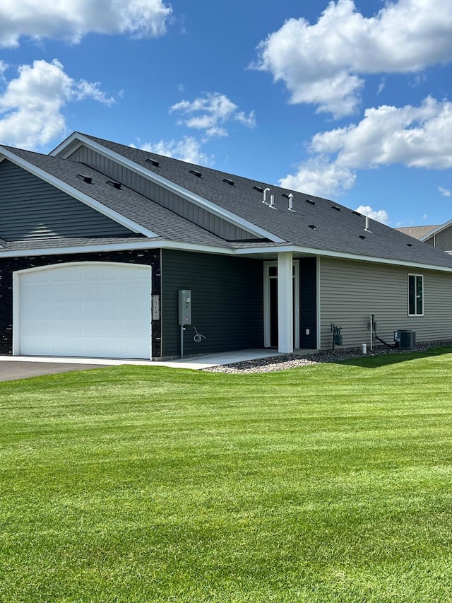 back of house featuring a garage, a lawn, and central AC