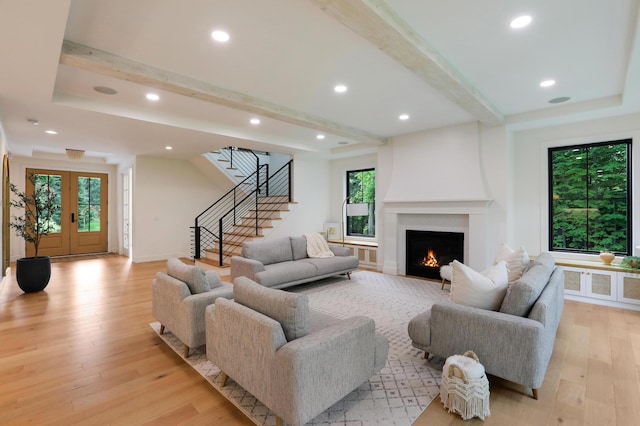 living room with beamed ceiling, light wood-type flooring, and french doors