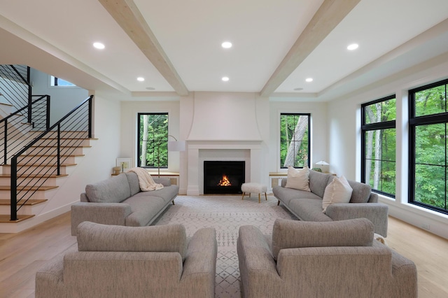 living room featuring beam ceiling, plenty of natural light, and a large fireplace