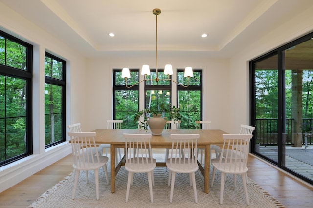 dining area featuring a tray ceiling, light hardwood / wood-style flooring, and a notable chandelier