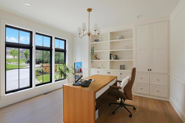 office featuring built in shelves, a notable chandelier, and light hardwood / wood-style flooring