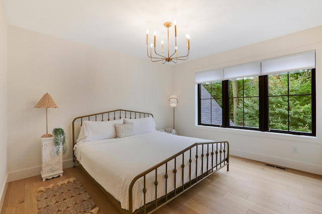 bedroom featuring multiple windows, an inviting chandelier, and light wood-type flooring