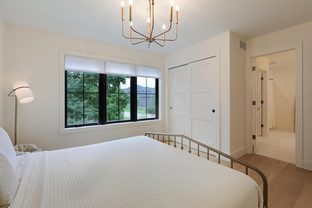 bedroom with a notable chandelier, wood-type flooring, and a closet