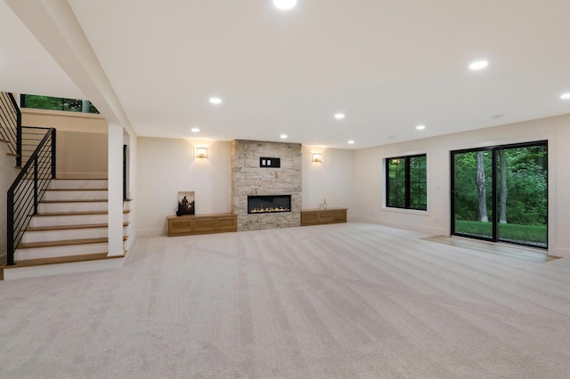 unfurnished living room with a stone fireplace and light carpet