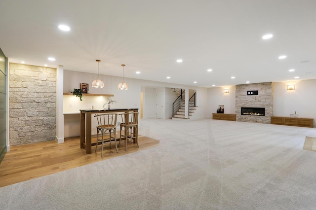 carpeted living room with a fireplace and bar area